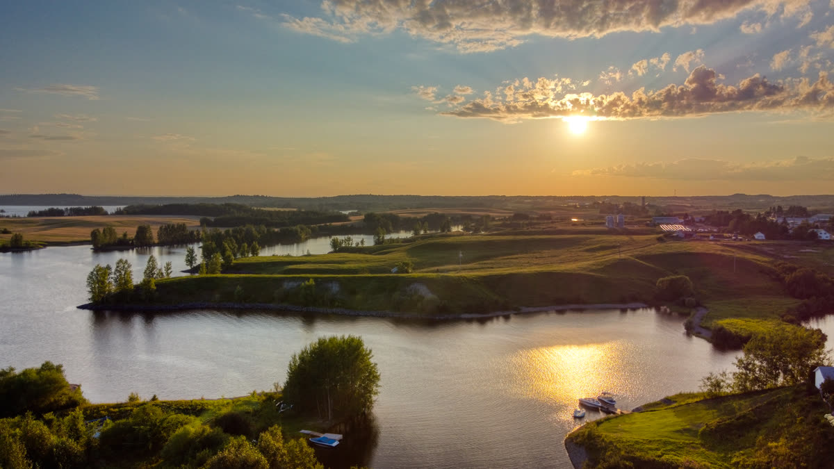 Soleil couchant sur la rivière à Saint-Coeur-de-Marie, au Lac-Saint-Jean, quelques bateaux amarrés et le village au loin