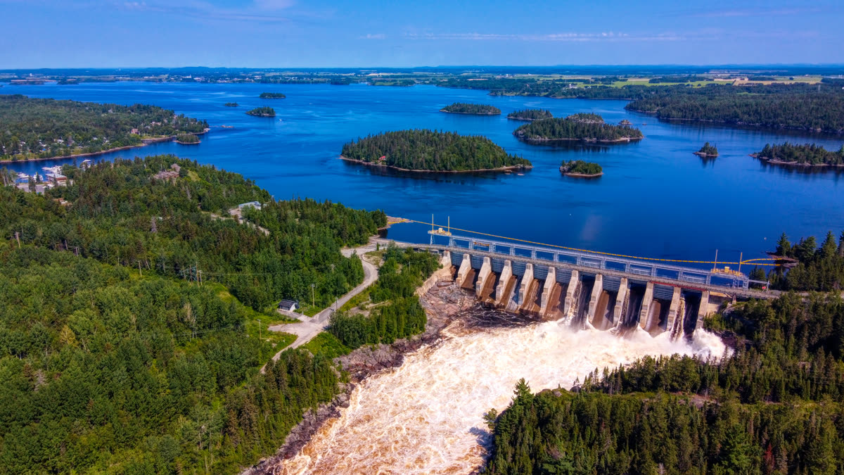 La Grande Décharge, au Lac-Saint-Jean : un barrage laissant échapper un torrent d'eau blanche dans un lac bleu bordé de forêt