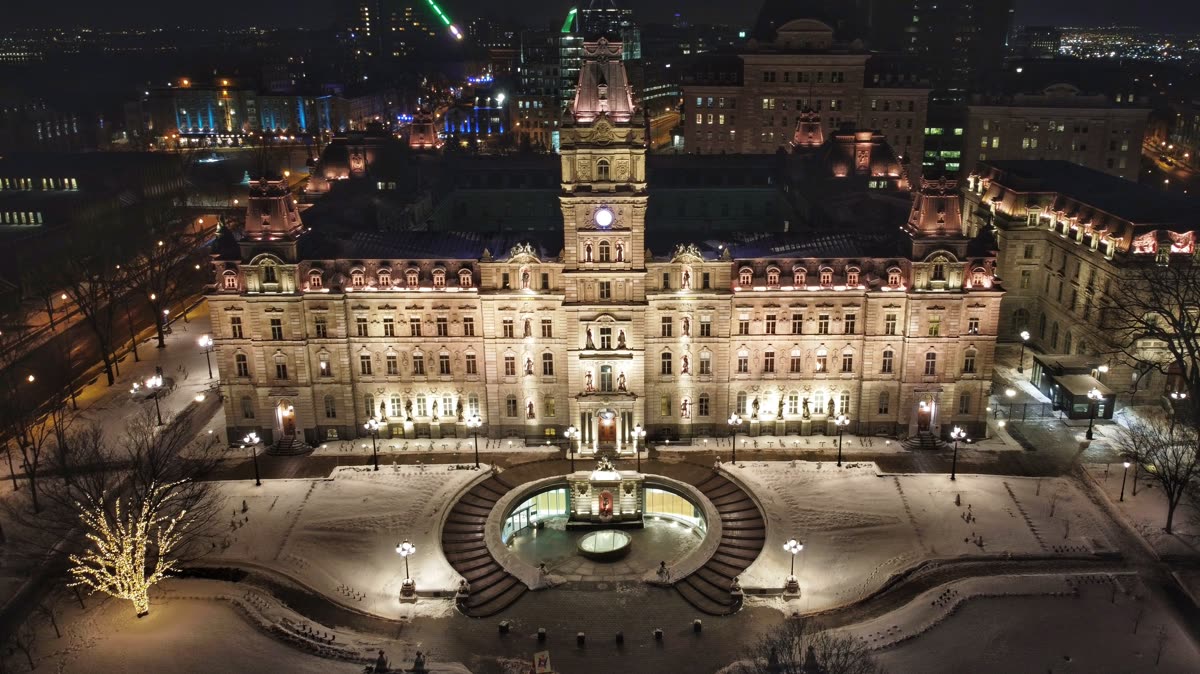 L'hôtel du Parlement du Québec éclairé la nuit, sa fontaine et ses jardins vus d'en haut