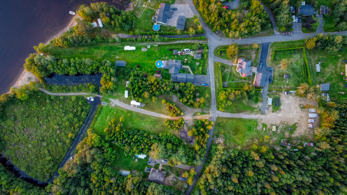 Une propriété boisée et ses bâtiments au Lac-Saint-Jean, vus du ciel en fin d'été