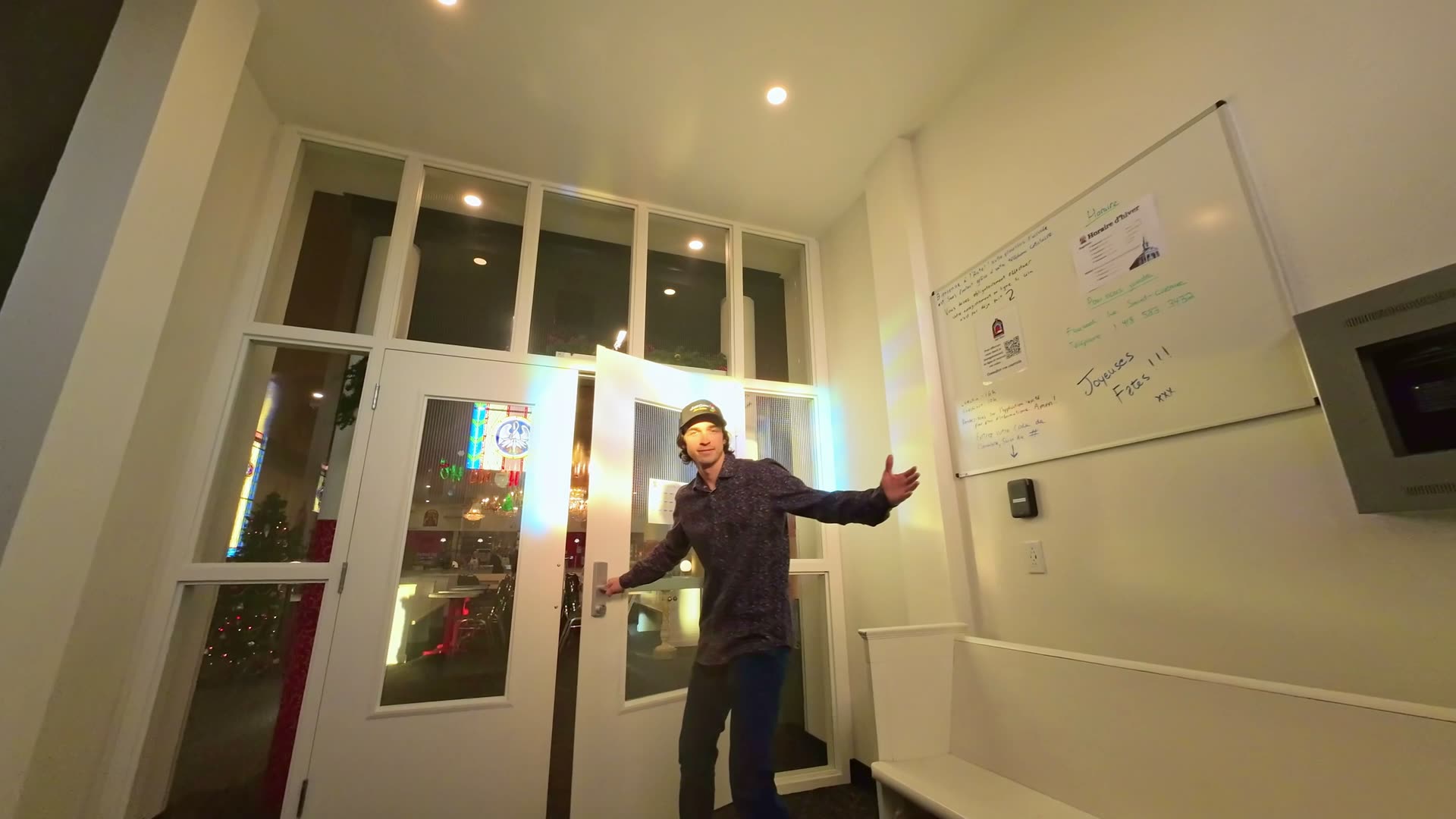 Intérieur d'un commerce, une personne ouvre grand les portes vitrées en soirée
