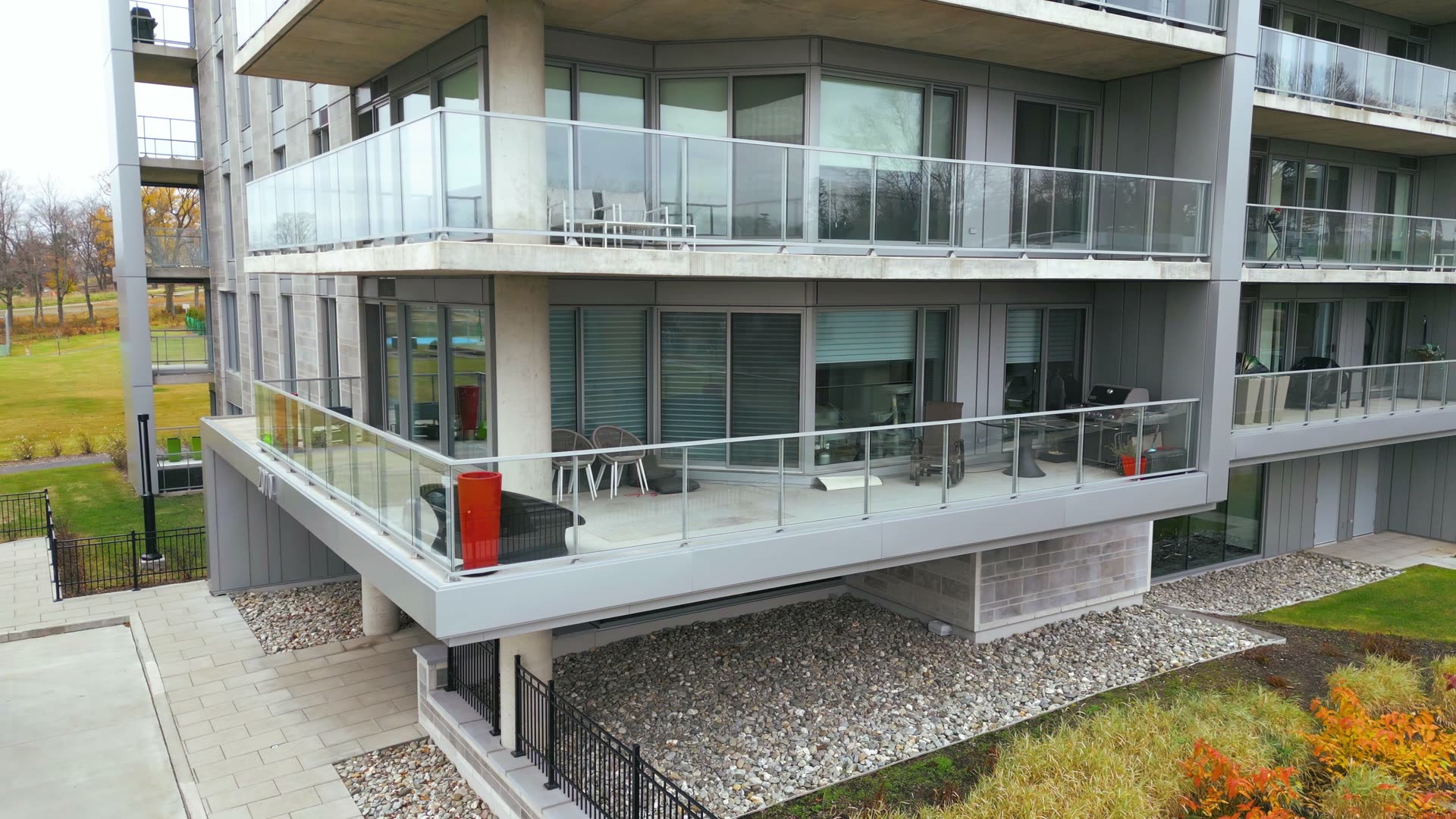 Vue rapprochée des balcons vitrés d'un immeuble à condos, en fin d'automne